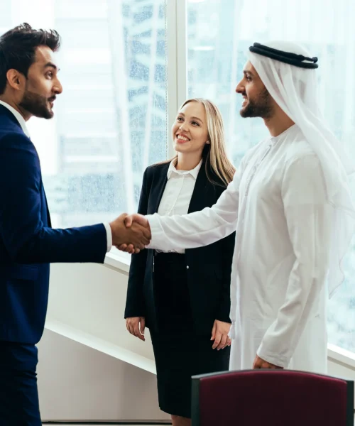 smiling-colleagues-looking-businessmen-shaking-hands-meeting-office